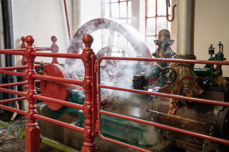 A huge, brightly coloured machine of the Victorian era belches steam.