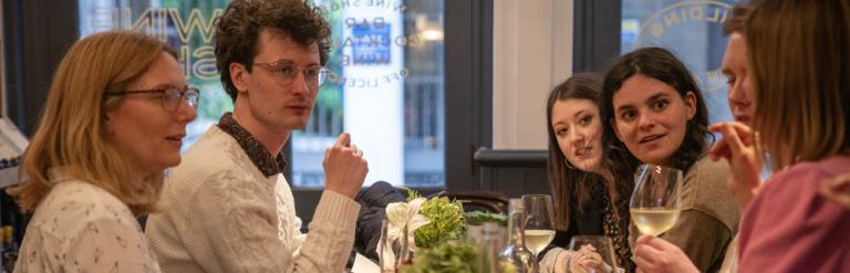 A group of colleagues have an animated discussion at a wine bar.