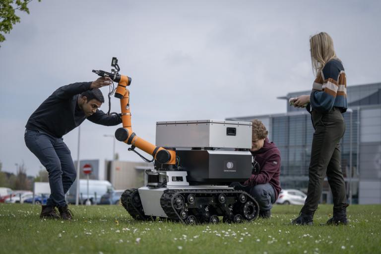 A team of engineers work on a robot rover outdoors.